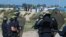 French riot police stand guard at the entrance to "the Jungle" as dozens of migrants try to storm trucks that are heading toward the ferry terminal in Calais, France, Sept. 21, 2016.