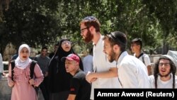 Sejumlah perempuan Palestina berteriak ke arah jemaah Yahudi setelah sempat bentrok antara polisi Israel dan warga Palestina di Masjid Alaqsa mengenai kunjungan jemaah Yahudi di Kuil Suci, di Yerusalem, Minggu, 18 Juli 2021. (Foto: Ammar Awad/Reuters) 