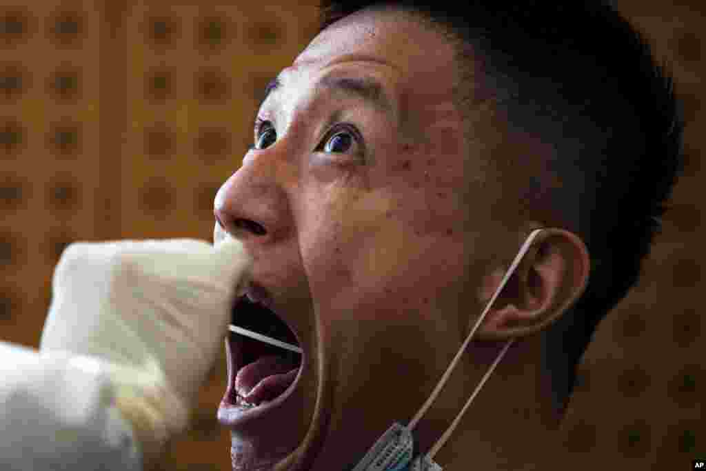 A medical staff takes a swab from a man who was invited to attend the commemorating conference on the 70th anniversary of the Chinese army entering North Korea to resist the U.S. army, for the coronavirus test, at a hotel in Beijing, Thursday, Oct. 22, 20