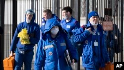 In this photo taken on Feb. 21, 2020, medical workers walk after checking passengers where a passenger was identified with suspected coronavirus after arriving from Kyiv at Kievsky (Kyiv's) rail station in Moscow. 