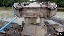 24일 필리핀 남부 잠보앙가델수에서 태풍 '덴빈'의 영향으로 발생한 홍수 때문에 무너진 다리 주변에 주민들이 모여있다.