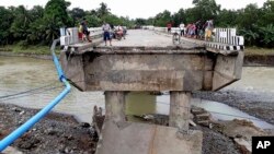 People gather on a bridge that was damaged by the flooding brought about by tropical storm Tembin, Dec. 24, 2017, in Zamboanga Del Sur in southern Philippines.