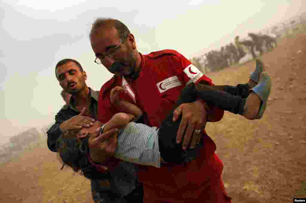 A member of the Syrian Arab Red Crescent carries a Kurdish Syrian refugee girl to the first aid tent after crossing the Turkish-Syrian border near the southeastern town of Suruc in Sanliurfa province, Sept. 25, 2014.