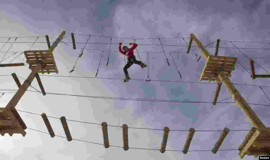 A woman climbs during the opening of a rope park at the Shimbulak Ski Resort in the Tien Shan mountains outside Almaty, Kazakhstan. The newly opened park is world&#39;s highest rope park mounted on artificial supports, said its designers. 