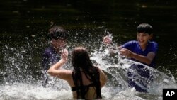 Leeann Gutiérrez, en el centro, salpica a sus hermanos Bo'Luke, a la izquierda, y Romeo, a la derecha, mientras se refrescan en el río Guadalupe, el miércoles 21 de agosto de 2024, en New Braunfels, Texas.