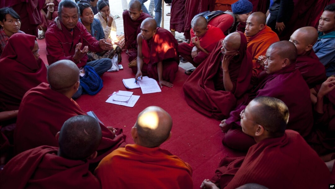 Activist known as Ko Kyaw, left background in blue pants, gestures during a meeting with protesting Buddhist monks who occupy the office entrance to the Chinese copper mine company Wan Bao Co. Ltd in northwestern Myanmar, Wednesday, Nov 28, 2012.