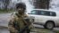 FILE - A Ukrainian soldier guards OSCE observers near the village of Shyrokyne, eastern Ukraine, April 19, 2015. 