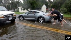 Warga mendorong mobil yang mogok terkena banjir akibat Badai Matthew di Florida (7/10). (AP/Eric Gay)