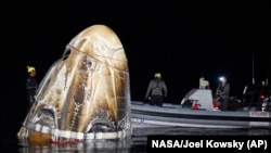 This photo provided by NASA shows support teams working around the SpaceX Dragon Endeavour spacecraft shortly after it landed in the Gulf of Mexico off the coast of Pensacola, Florida, Oct. 25, 2024. (NASA/Joel Kowsky via AP)