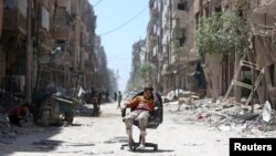 Un Syrien assis sur une chaise le long d'une rue détruite de la ville de Douma, à Damas, en Syrie, le 16 avril 2018.