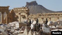 Syrian army soldiers stand on the ruins of the Temple of Bel in the historic city of Palmyra, in Homs Governorate, Syria, April 1, 2016. The Fakhreddin's Castle is seen in the background. 