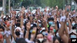 Anti-coup protesters raise decorated Easter eggs along with the three-fingered symbols of resistance during a protest against the military coup on Easter, April 4, 2021, in Yangon, Myanmar. 