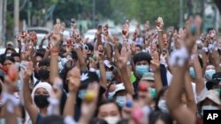 Anti-coup protesters raise decorated Easter eggs along with the three-fingered symbols of resistance during a protest against the military coup on Easter, April 4, 2021, in Yangon, Myanmar.
