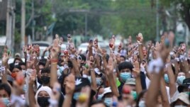 Anti-coup protesters raise decorated Easter eggs along with the three-fingered symbols of resistance during a protest against the military coup on Easter, April 4, 2021, in Yangon, Myanmar.