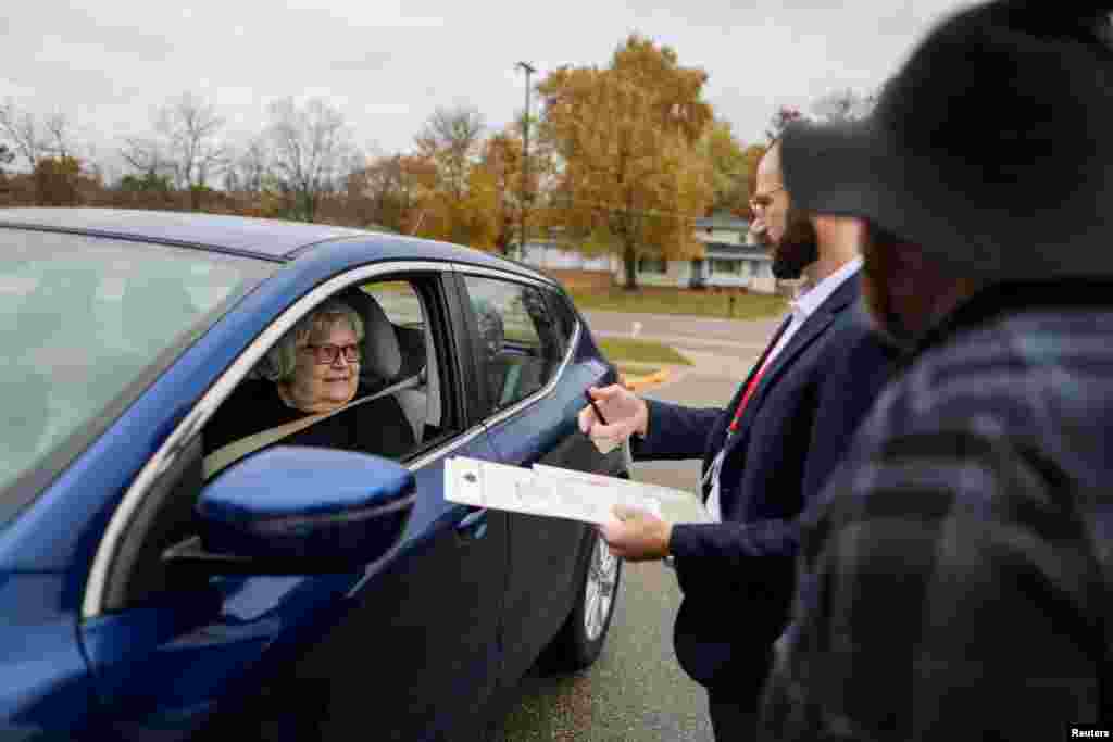 Election officials Owen O&#39;Keefe and Brandon Rieckhoff assist Mary Miller, who has a mobility issue, with the voting process outside Faith Lutheran Church in Grand Rapids, Michigan, Nov. 5, 2024.