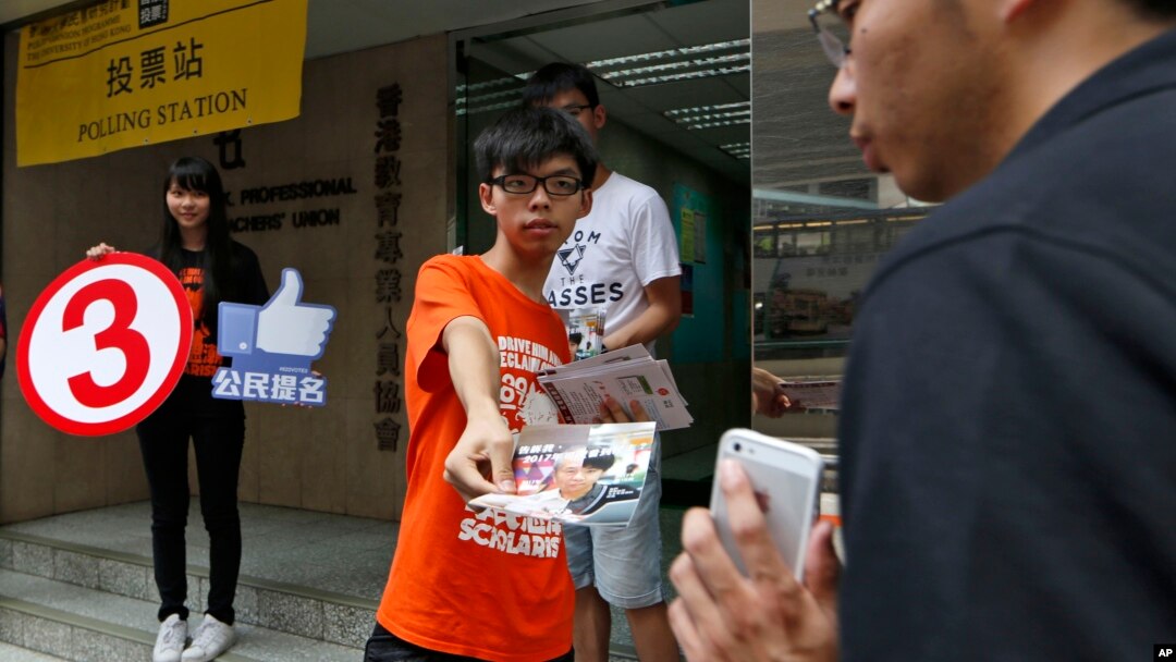 Joshua Wong, a student leader in the Occupy Central movement handouts leaflets near a polling station to urge people to vote on the last day for an unofficial referendum on democratic reform in Hong Kong, June 29, 2014.