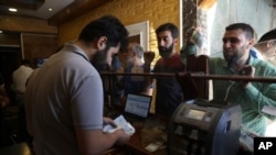 People exchange money in the city of Idlib, Syria, June 20, 2020. In the northwestern province of Idlib, the last remaining Syrian rebel stronghold, some people have started using the Turkish lira instead of the Syrian pound. 