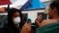 FILE - Mexican Health Ministry representatives give migrants free shots for the flu, hepatitis B, tetanus, and preventible children's diseases at the Barretal shelter for migrants in Tijuana, Mexico, Dec. 6, 2018.