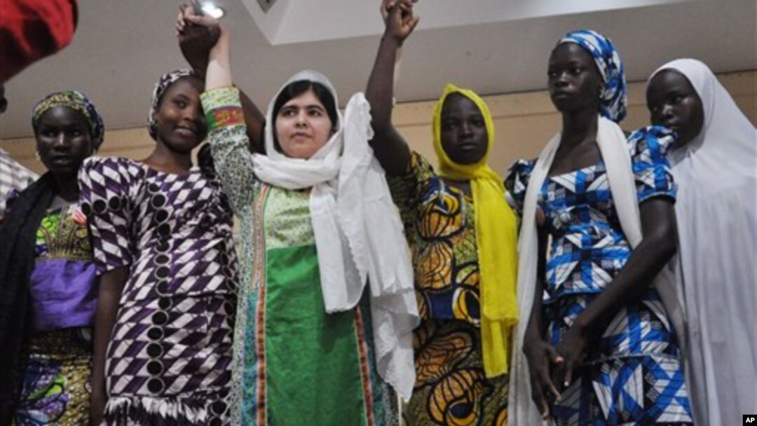 Aktivis Pakistan Malala Yousafzai, mengangkat tangan beberapa siswi di Chibok yang lolos dari penculikan dalam konferensi pers di Abuja, Nigeria, Senin (14/7).