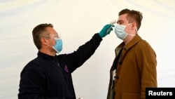 FILE PHOTO: An employee checks the temperature of another employee on arrival to work as PSA Peugeot re-opens after shutting down due to the coronavirus disease (COVID-19) outbreak in Trnava, Slovakia, Apr. 17, 2020. 