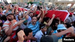 Supporters of deposed Egyptian President Mohamed Morsi carry mock coffins during a symbolic funeral for the four men killed during clashes with police outside the Republican Guard headquarters a day earlier, in Cairo, July 6, 2013. 
