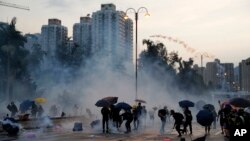 Para pengunjuk rasa melempar tabung gas air mata di Hong Kong, Senin, 5 Agustus 2019. (AP Photo / Kin Cheung)