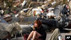 A woman cries while sitting on a road amid the destroyed city of Natori, Miyagi Prefecture in northern Japan, March 14, 2011.