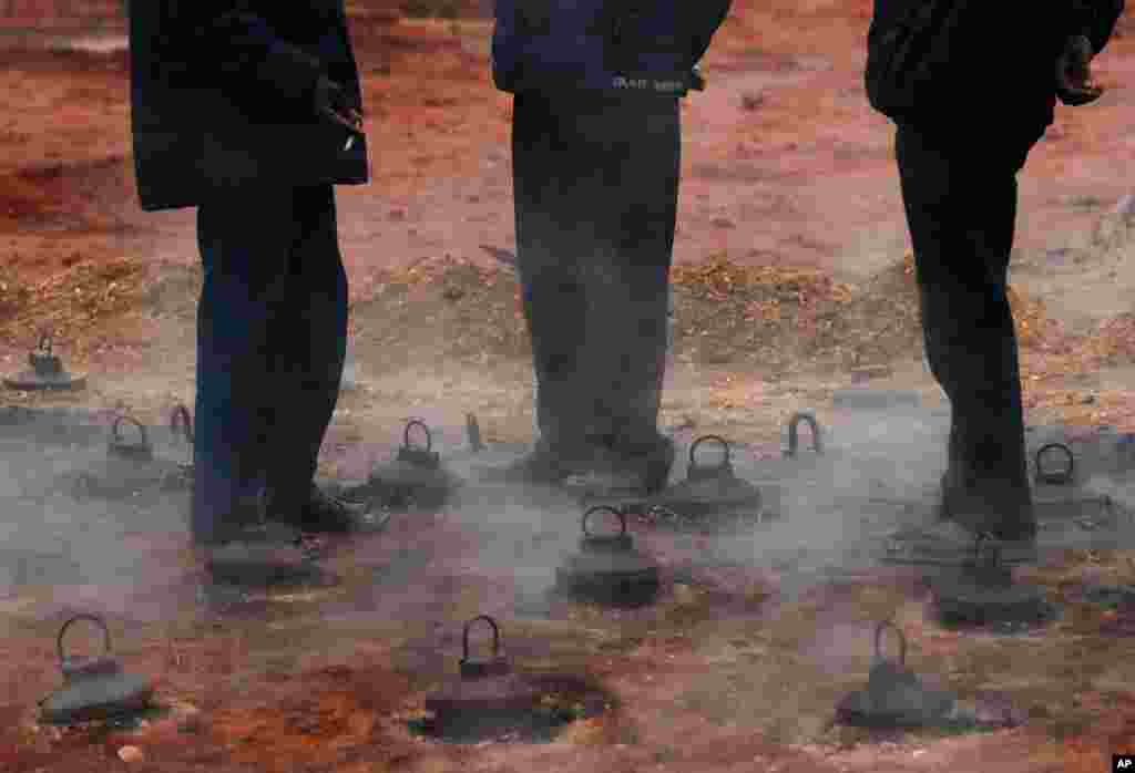 Workers stand over a furnace at a brick factory to keep themselves warm on the outskirts of Kathmandu, Nepal.