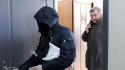 Chief of Belarusian Association of Journalists (BAJ) Andrei Bastunets, right, and Belarusian policemen leaves the BAJ office after raid in Minsk, on Feb. 16, 2021.