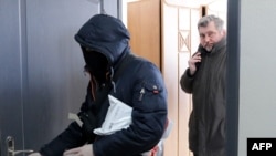 Chief of Belarusian Association of Journalists (BAJ) Andrei Bastunets, right, and Belarusian policemen leaves the BAJ office after raid in Minsk, on Feb. 16, 2021.