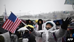 Seorang pendukung Presiden Yoon Suk Yeol yang dimakzukan memegang bendera Amerika saat mengikuti unjuk rasa di dekat kediaman resmi Yoon di Seoul, Korea Selatan, di tengah salju lebat, Minggu, 5 Januari 2025. (Foto: Philip Fong/AFP)