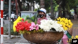 A flower vendor wearing a face mask to protect against the coronavirus waits for customers in Hanoi, Vietnam, Monday, Aug. 3, 2020. Vietnam has tightened travel and social restrictions after the country's death toll of COVID-19 to six. (AP Photo/Hau)