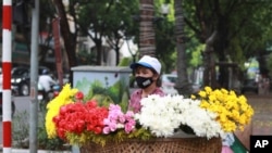A flower vender wearing a face mask to protect against the coronavirus waits for customers in Hanoi, Vietnam, Monday, Aug. 3, 2020. Vietnam has tightened travel and social restrictions after the country's death toll of COVID-19 to six. (AP Photo/Hau…