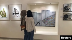 Pengunjung melihat karya seni dalam pameran yang diadakan untuk mengumpulkan dana bagi Gaza, di Galeri Orient di Amman, Yordania 25 Mei 2021. (REUTERS / Jehad Shelbak)