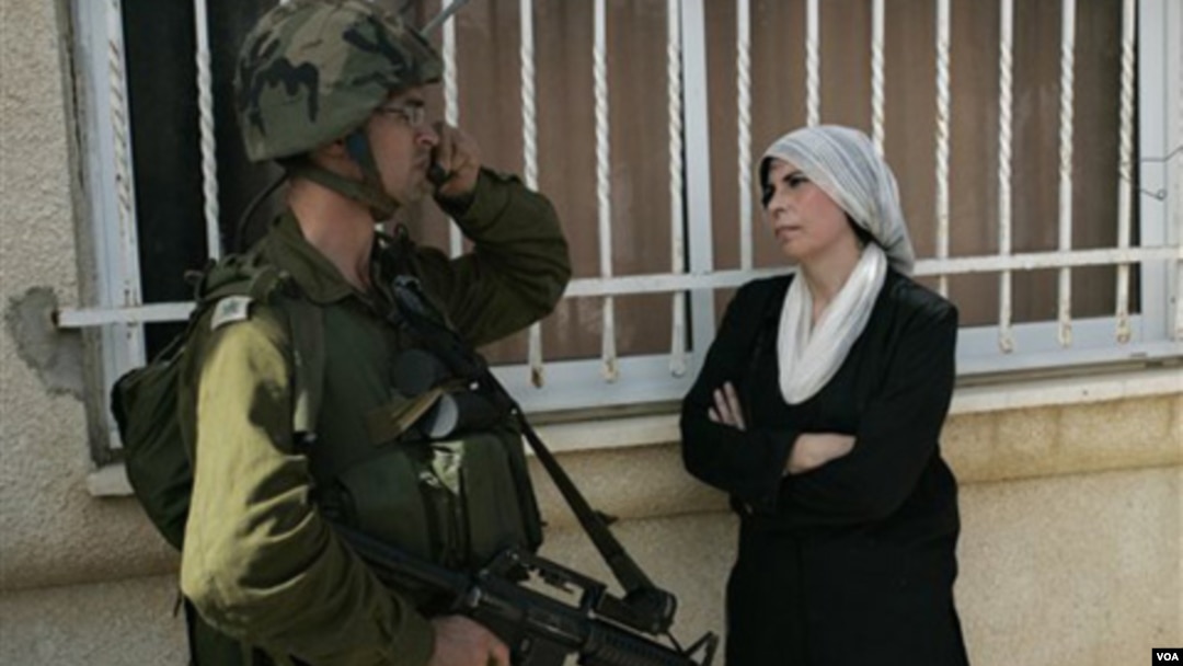 Seorang wanita Palestina berdiri di dekat tentara Israel saat aksi protes di Tepi Barat (dokumentasi).
