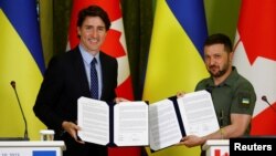 Perdana Menteri Kanada Justin Trudeau dan Presiden Ukraina Volodymyr Zelenskyy menunjukkan deklarasi bersama kedua negara dalam konferensi pers di tengah serangan Rusia ke Ukraina, di Kyiv, Ukraina, Sabtu, 10 Juni 2023. (Foto: Valentyn Ogirenko/Reuters)