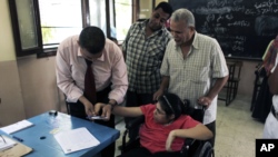 6月17日在开罗的一个投票战，一位选举工作人员帮助一位残疾人投票