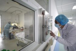 FILE - A medical worker calls his colleague inside an isolated ward at Jinyintan Hospital in Wuhan, the epicenter of the novel coronavirus outbreak, in Hubei province, China, Feb. 13, 2020.