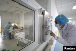 FILE - A medical worker calls his colleague inside an isolated ward at Jinyintan Hospital in Wuhan, the epicenter of the novel coronavirus outbreak, in Hubei province, China, Feb. 13, 2020.