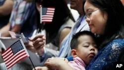 FILE - And immigrant from China holds her three-year-old son and a U.S. flag during a naturalization ceremony at the New York Public Library, in New York City, July 3, 2018. 