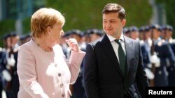 Kanselir Jerman Angela Merkel (kiri) menyambut Presiden Ukraina Volodymyr Zelenskiy di Berlin hari Selasa (18/6). 