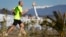 A man jogs on a sunny day as the Olympic Cauldron and flame are seen in the background in the Olympic Park during the 2014 Winter Olympic Games, Feb. 12, 2014.