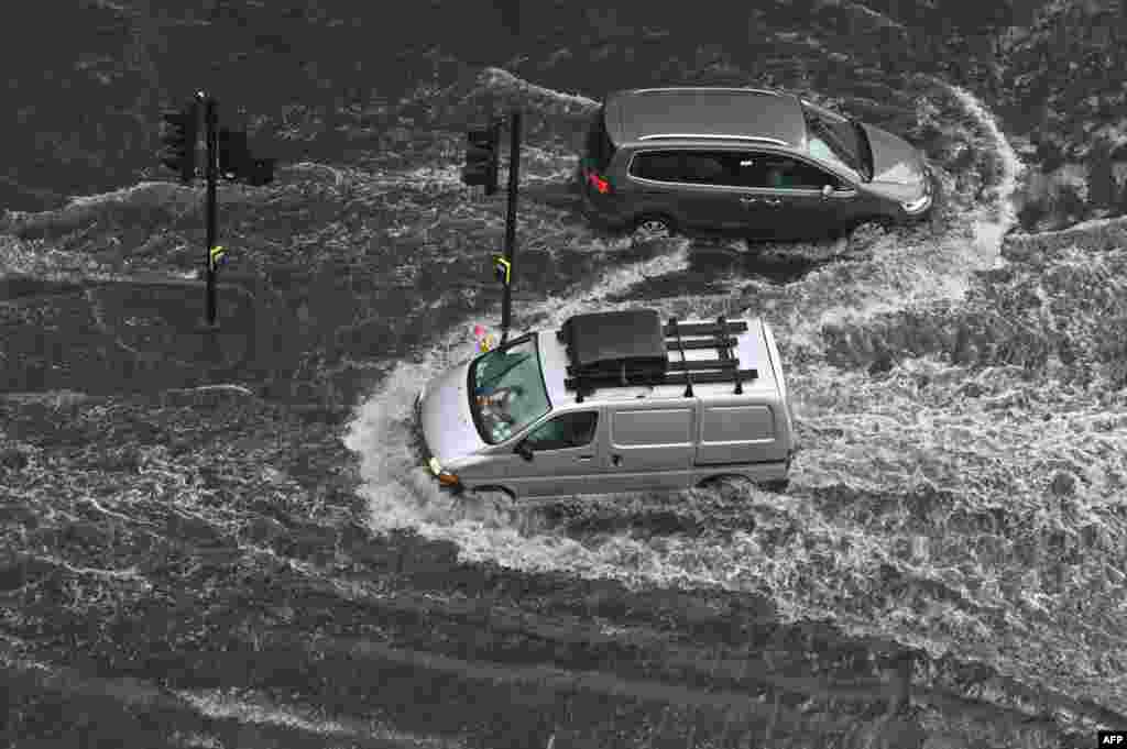 Vehicles drive through deep water on a flooded road in The Nine Elms district of London on July 25, 2021 during heavy rain.