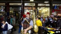 Ishaaq Kremed, a tamarind juice seller, calls on customers in the covered Hamidiyah market in the old part of the capital Damascus, on April 8, 2021. 