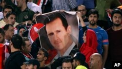 Des supporters de football syriens tiennent une affiche de leur président, Bachar al-Assad, avant un match contre l'Iran, au stade Azadi à Téhéran, en Iran, le 5 septembre 2017.