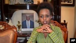 FILE—In this Sunday, May 14, 2017 file photo, women's rights activist and presidential candidate Diane Shima Rwigara, 35, is photographed next to a portrait of her father, business tycoon Assinapol Rwigara, at her home in Kigali, Rwanda. 