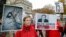 FILE - Lucie Morillon, head of research at French watchdog of Reporters Sans Frontieres (Reporters without Borders) holds a banner depicting Syrian human rights activist Mazen Darwish during a protest against violence in Syria, in Paris, Oct. 20, 2012.