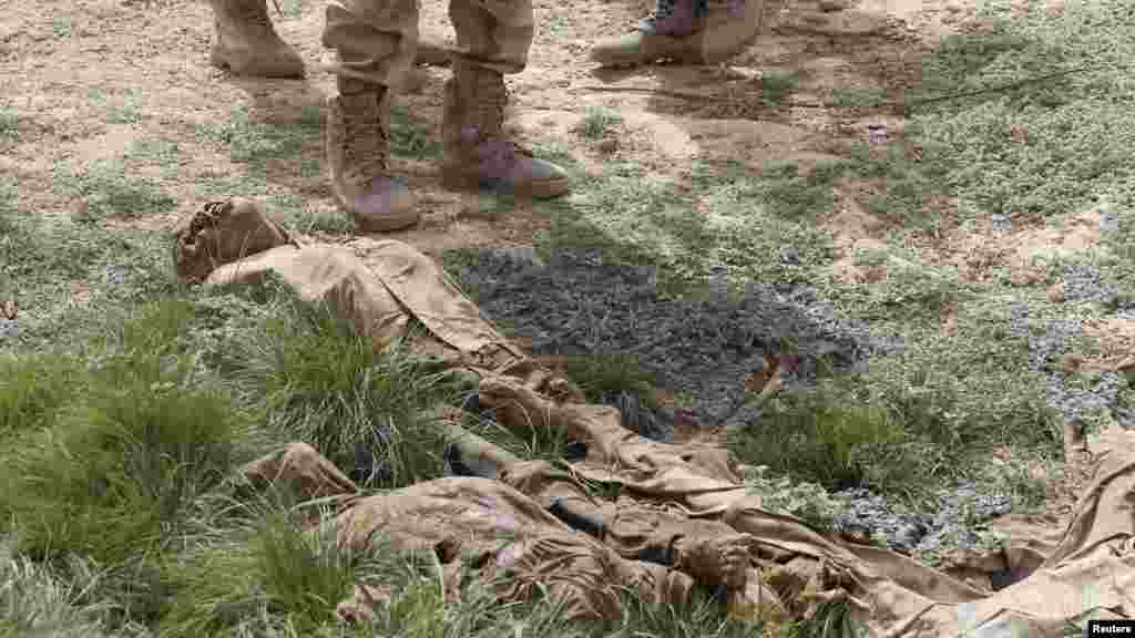 Des soldats nigériens regardent les cadavres en décomposition dans une fosse commune à Damasak, ville récemment reprise de Bokok Haram, au Nigeria, le 20 Mars 2015.