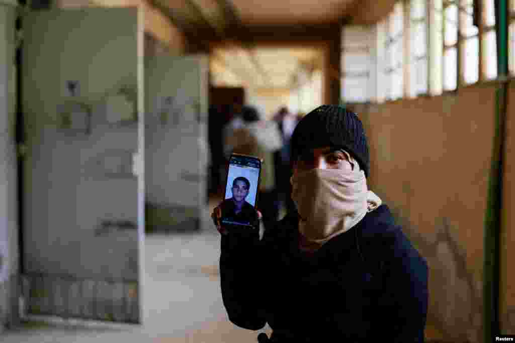 Hayat al-Turki holds a phone with the picture of her brother at Sednaya prison as she searches the prison in the hope of finding her relatives, in Sednaya, Syria, Dec. 11, 2024.