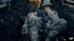 A Ukrainian soldier sits in a trench near Russian positions near Bakhmut, Donetsk region, Ukraine, March 5, 2023. 